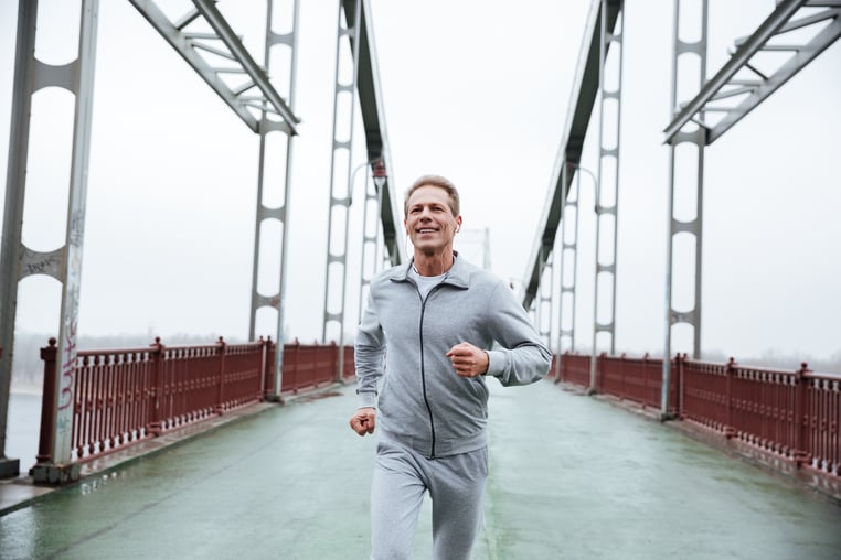 smiling-man-in-gray-sportswear-running-on-bridge_BLre7ODQdne-1